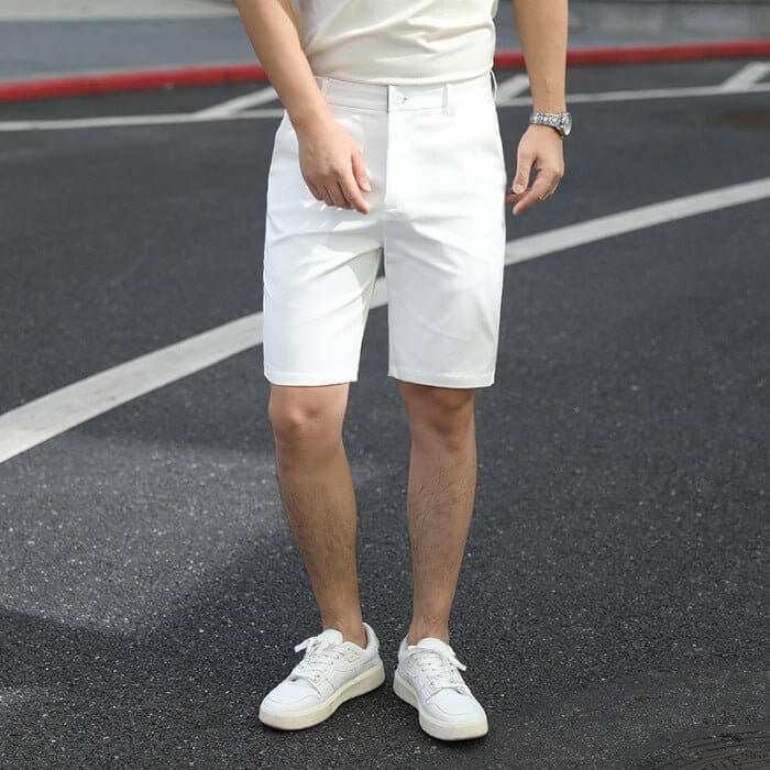 Men's white summer pants with a casual fit and elastic waistband worn with white sneakers on asphalt road
