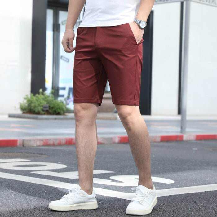 Man wearing casual loose-fitting wine red men's summer pants with elastic waistband and white sneakers outdoors