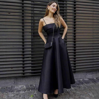 Woman wearing elegant black sleeveless backless maxi summer dress with spaghetti straps and small shoulder bag outdoors