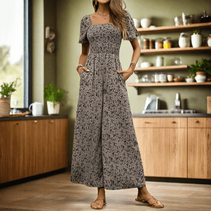 Woman wearing a fashion wide-leg pants jumpsuit with printed pattern, square neckline, and short puff sleeves in a modern kitchen setting