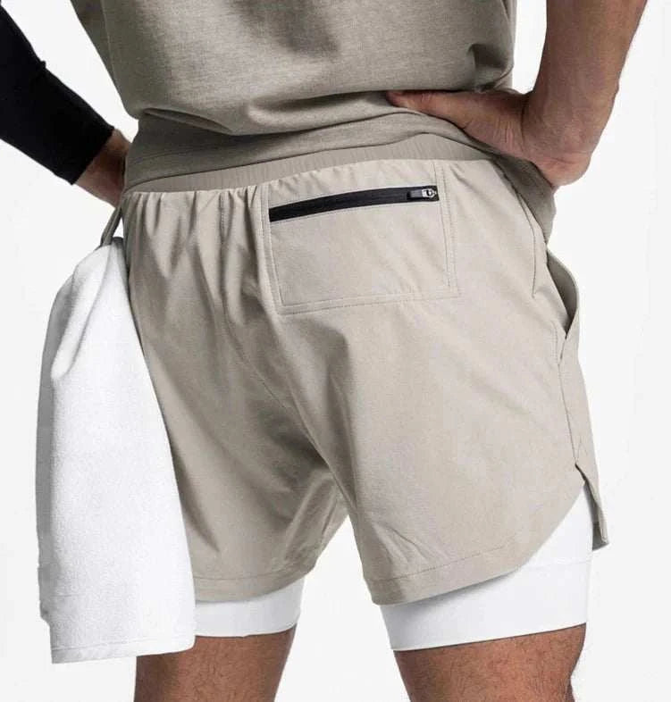 Men wearing beige 2 in 1 fitness gym shorts with breathable inner tights and a towel loop carrying a white towel.