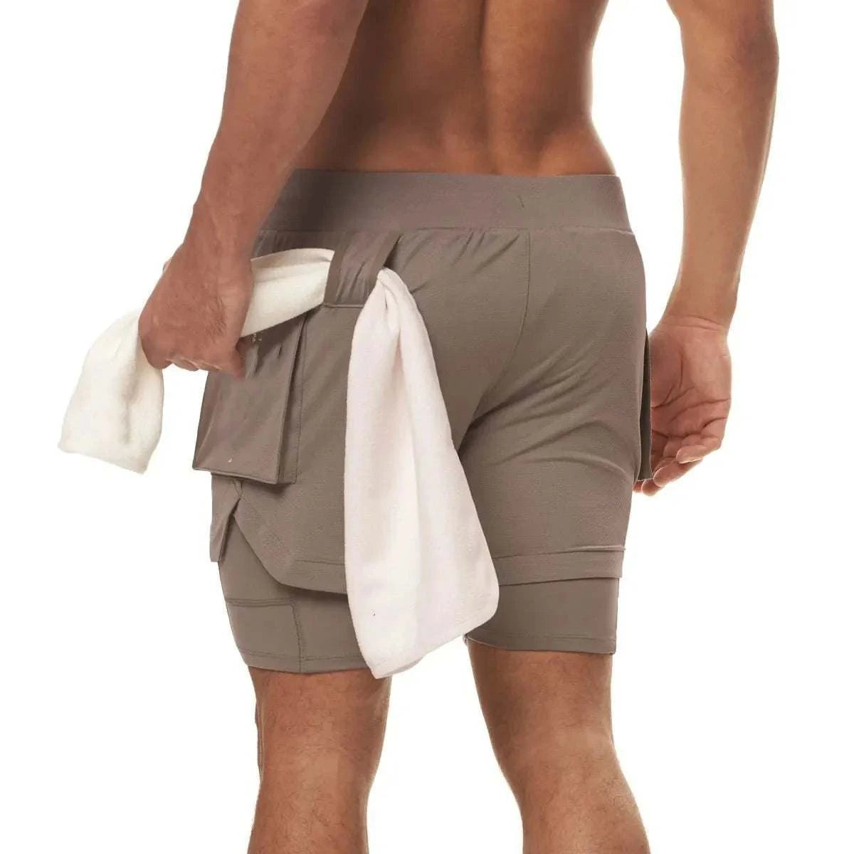 Men 2 in 1 running training joggers gym shorts with phone pocket in beige worn by male model holding towel from back view
